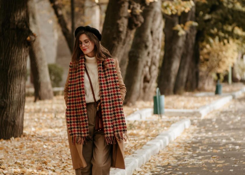 beautiful young woman in beret and coat walks in the autumn city