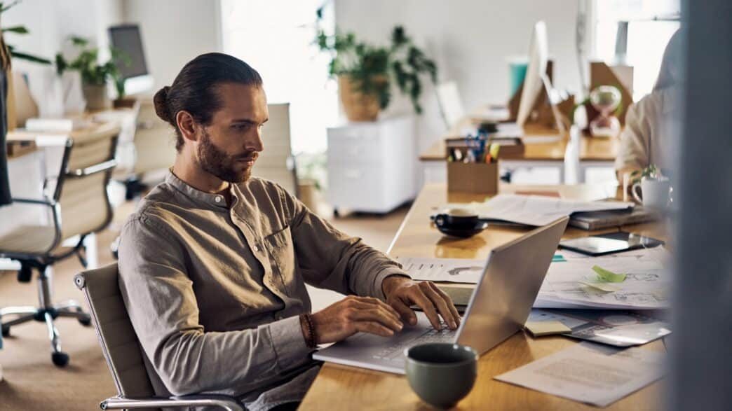 young-caucasian-businessman-using-a-laptop-sitting-at-a-desk-at-work-picture-id1394396760-1-1044×587