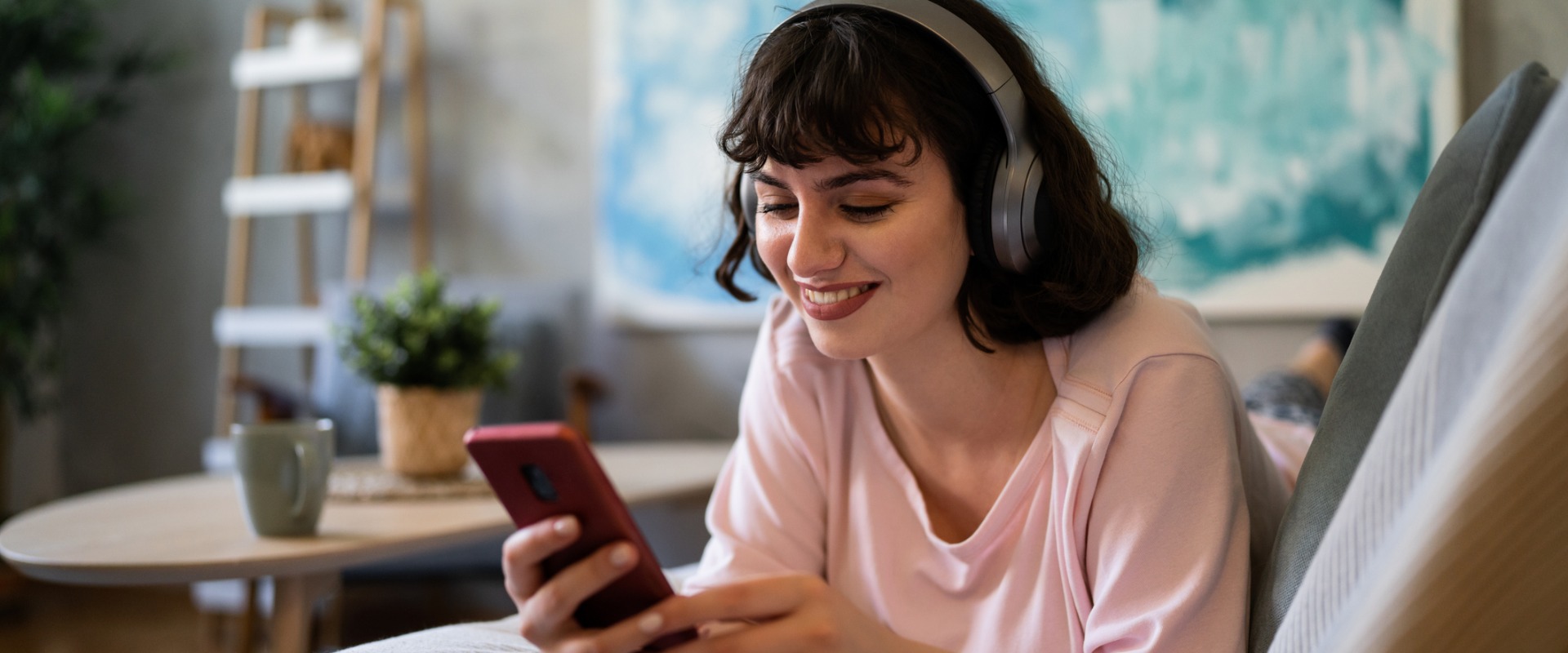 caucasian-woman-lying-on-the-sofa-using-mobile-phone-while-listening-picture-id1408269768